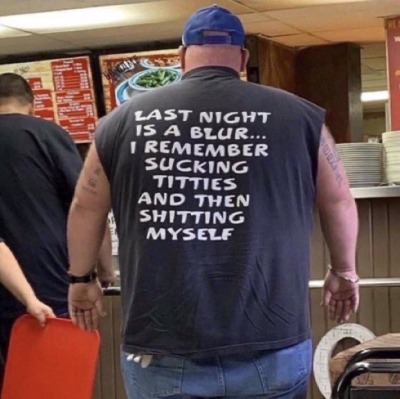 Man in line for fast food. The back of his shirt says: 'Last night is a blur... I remember sucking titties and then shitting myself