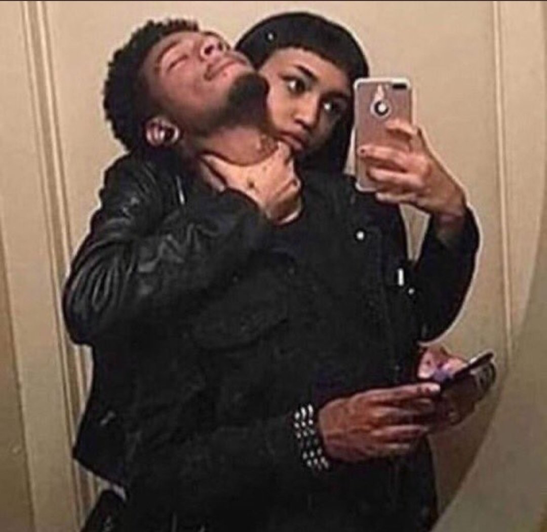 Mirror selfie of a guy and girl. Girl has her hand around the man's throat.